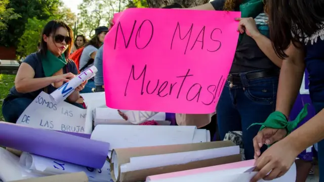 Mujeres en una protesta con un cartel que dice "No más muertas".