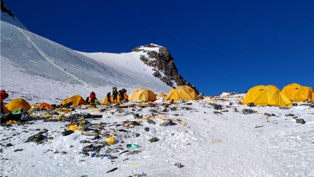 Next to yellow tents, discarded climbing equipment and rubbish left scattered at Camp 4