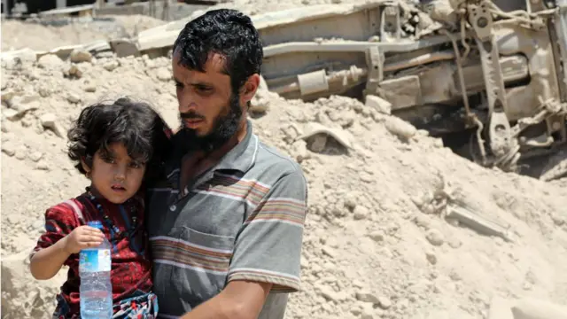 أحد المدنيين النازحين من الموصل القديمة وهو يحمل ابنته