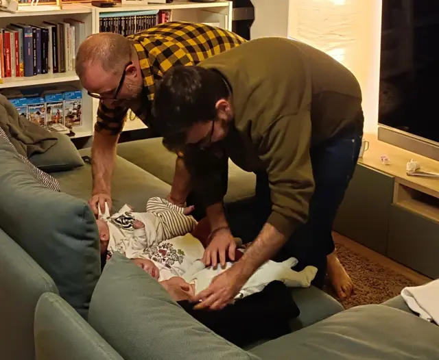 Ismael y Miguel atienden a las niñas en el sofá de la casa.