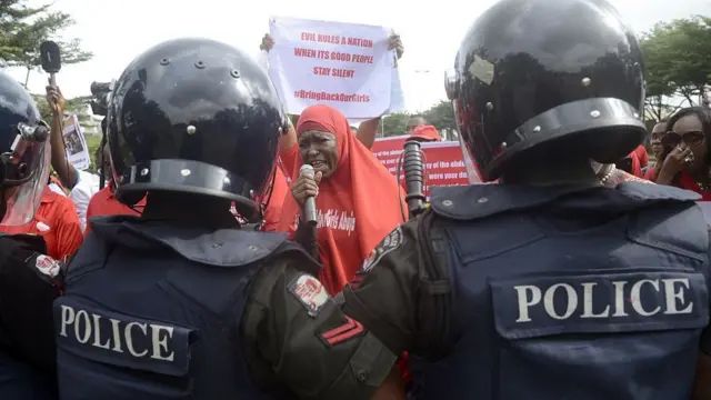 Riot police officers dey in front of pipo wey dey protest say make goment epp resuce pikin wey Boko Haram don kidnap