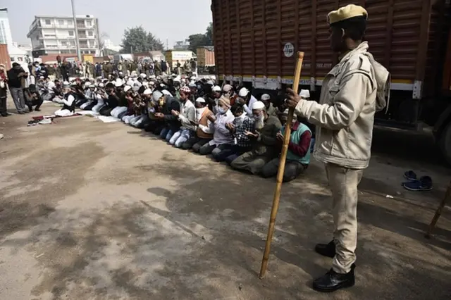 A police personnel stands guard as Muslim devotees offer Namaz at Sector 37 parking area, on December 3, 2021 in Gurugram, India.