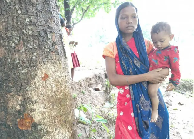 पेड़ में लगी गोली के निशान दिखाती जीरामनी देवी