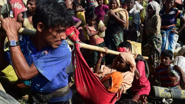 कपड़े के जुगाड़ झूले में महिला को ले जाता आदमी, पीछे भीड़