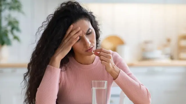 Mulher com carasite de aposta afunressaca tomando um comprimido