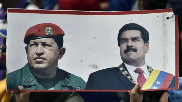 Manifestante segura pôster com fotoslucky slots paga mesmoHugo Chávez e Nicolás Maduro