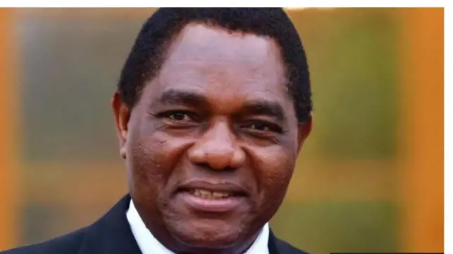 Aarẹ orilẹede Zambia, Hakainde Hichilema ninu aṣọ oyinbo, awọ dudu ati funfun ni aṣo naa. Aarẹ naa n rẹrin-in muse ninu aworan yii