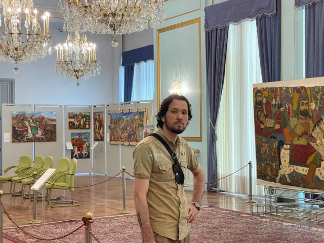 مردی در برابر تابلوها ایستاده است 