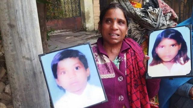 Neetu Kumari segurando as fotos dos filhos desaparecidos 