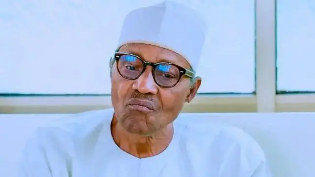 Marigayi Muhammadu Buhari sanye da fararen kaya yana sauraron karatu a masalalcin fadar shugaban ƙasa.
