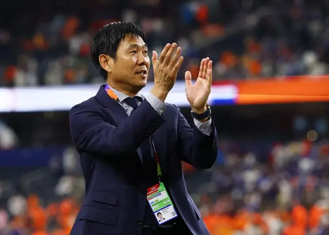 ダークスーツ姿の森保監督がピッチで両手を前に上げている