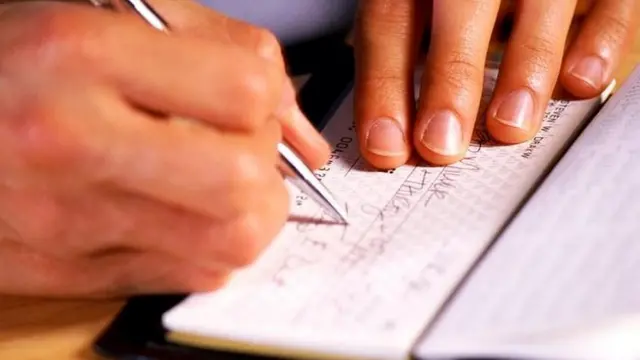 Hombre firmando un cheque.