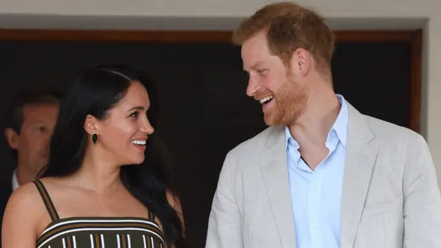 Meghan Markle e o príncipe Harry sorrindo um para o outro