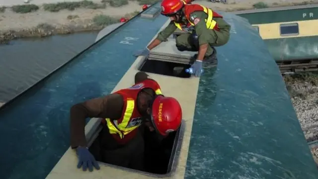 巴基斯坦信德省納瓦布沙阿客運火車出軌事故現場救援人員在扭曲的車廂殘骸中攀爬（6/8/2023）