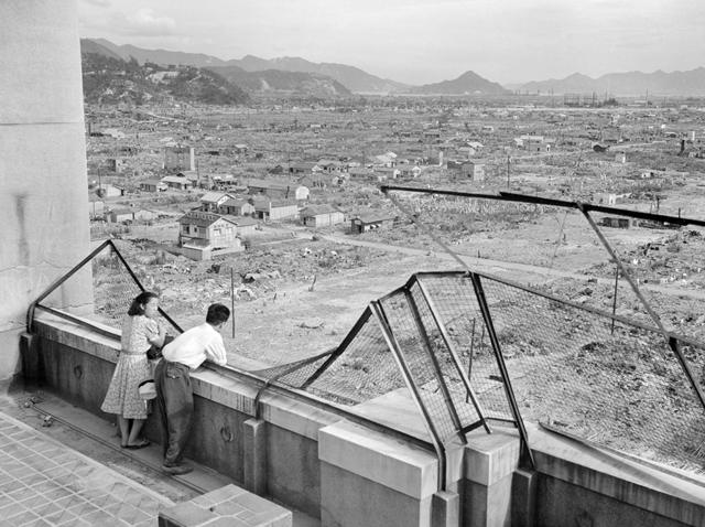 一对夫妇在被毁坏的大楼上远眺城市废墟。