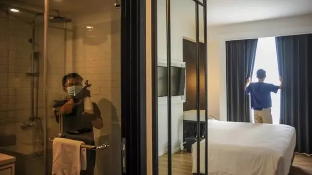 Pegawai hotel menyemprotkan disinfektan di kamar di tengah pandemi virus corona Covid-19.