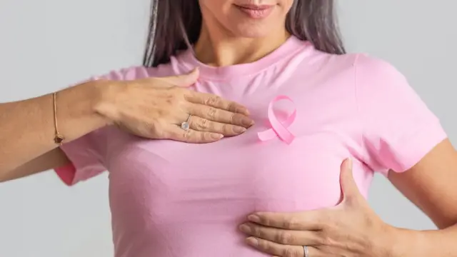 Una mujer se hace un autoexamen mamario.