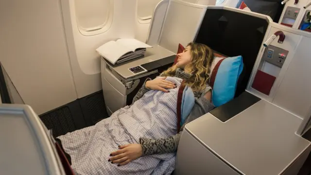Una mujer duerme en un asiento de primera clase de un avión