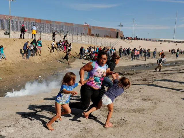 Uma família corre perto do muro fronteiriço