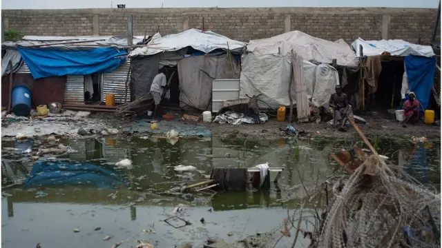 People living in temporary sheds next to a mosquito infested pond in DRC