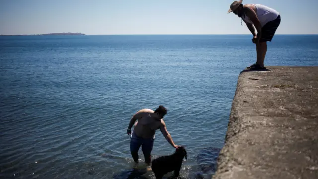 سكان محليون يبحثون عن أفضل الطرق لمجابهة الحر اللاهف الناتج عن "قبة حرارية" تقبع فوق إقليمي بريتيش كولومبيا وألبرتا الكنديين، وذلك بالسباحة في شاطئ ويلوز بيتش