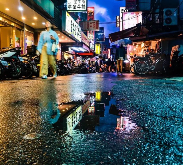 Un charco refleja los carteles de Taipei, Taiwán.