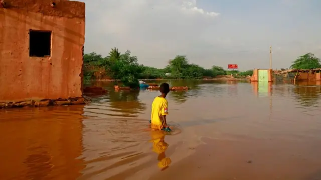 A Sudanese boy wades through a flooded street at alqamayir area in the capital's twin city of Omdurman, on August 26, 2020.