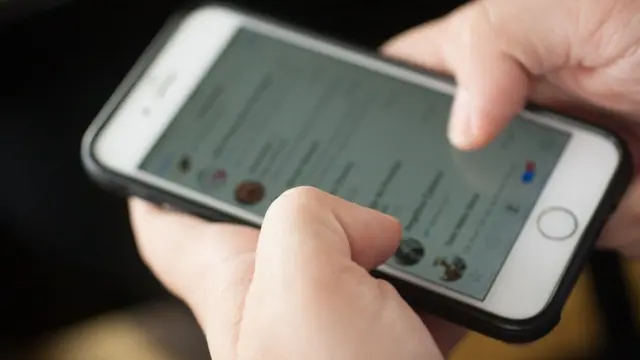 Uma mão segurando um smartphone - a pessoa está usando o WhatsApp