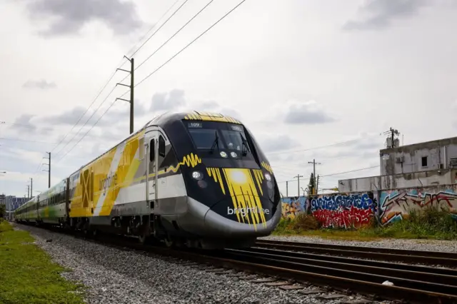 Un tren Brightline pasa junto a un muro con pintadas en la ciudad de Miami.