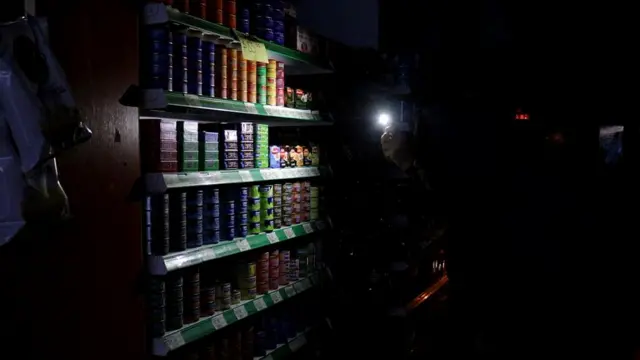 Люди используют экраны телефонов, чтобы осветить полки супермаркета в Буэнос-Айресе (Аргентина)