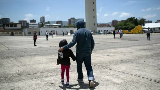 A father walking with his daughter at the airport in Brownsville, TX, towards a deportation flight