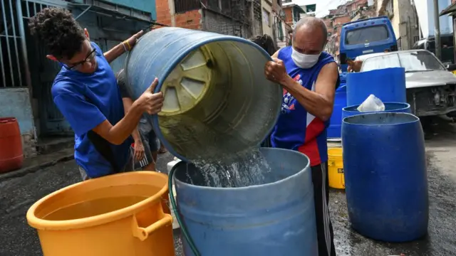 Homens enchem galão com águabet365starCaracas