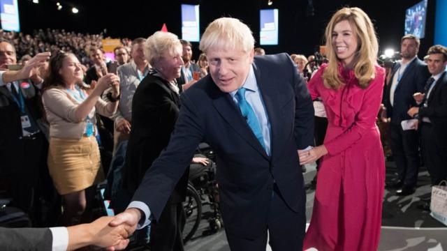 Prime Minister Boris Johnson leaves the stage with his partner Carrie Symonds after delivering his speech during the Conservative Party Conference at the Manchester Convention Centre.