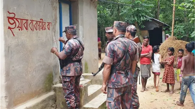সন্দেহভাজন মাদক ব্যবসায়ীর বাড়ির দেয়ালে 'ইয়াবা ব্যবসায়ীর বাড়ি' লিখে চিহ্নিত করে রাখছে নিরাপত্তা বাহিনী।