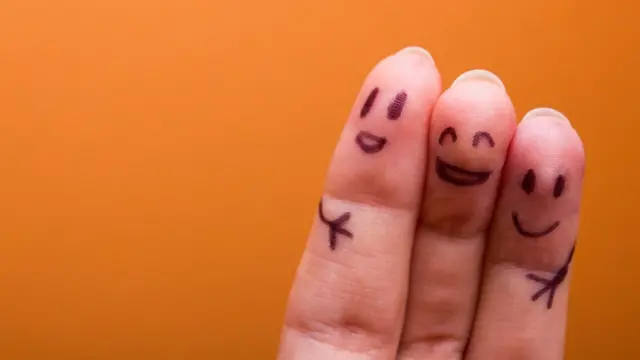 Dedos con caras pintadas abrazándose