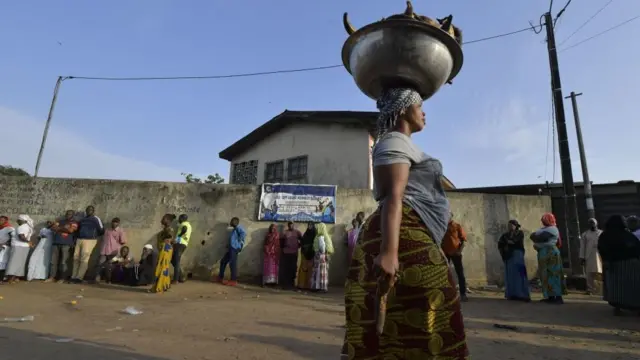 Umudandaza wo mw'ibarabara aciye imbere y'umurongo w'abaje gutora imbere b'ibiro vy'amatora i Abobo, umuhana w'i Abidjan, itariki 31 z'ukwa cumi 2020.