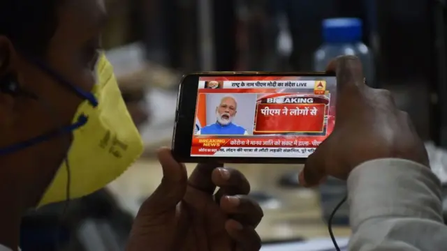 জাতির উদ্দেশ্যে প্রধানমন্ত্রী মোদীর দেওয়া ভাষণ দেখছেন মাস্ক পরিহিত এক ব্যক্তি।