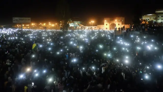 A crowd using their mobile phone lights at a sit-in at the military HQ in Khartoum, Sudan - Sunday 7 April 2019