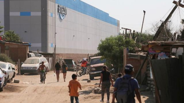 People walk near an informal settlement next the new Amazon fulfilment centre, which is under construction at the RMSG Alamar Industrial Park, in Tijuana, Mexico September 7, 2021.