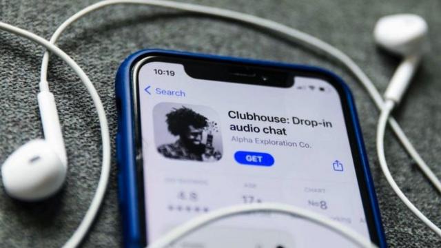 Un iPhone con la aplicación Clubhouse abierta y un par de auriculares