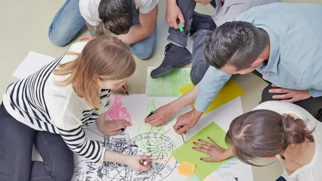 Adultos y niños coloreando en el piso
