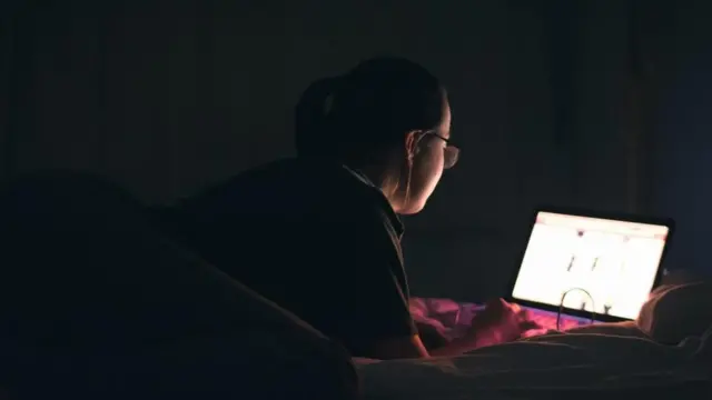 سيدة تعمل في منزلها على شاشة كمبيوتر محمول