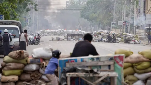 Protesters take cover behind barricades during a demonstration against the military coup in Mandalay, Myanmar March 21, 2021.