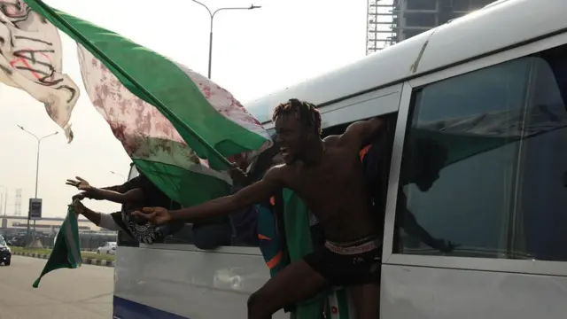 Some protesters wave flags inside dia cars, odas wave fliers and posters wey carry different messages