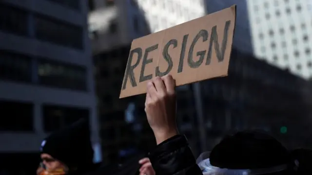 Manifestante levanta placa dizendo: 'Resign'