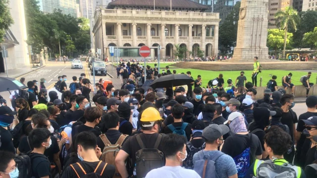 示威者聚集在一起讨论接下来的行动，有人表示要继续往前，有人担心游行队伍拉长会导致人群不集中。