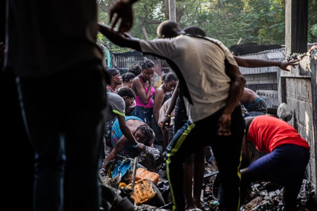 Gente busca entre lo que queda tras el incendio en un campo de desplazados en Puerto Príncipe, Haití, el 21 de diciembre de 2025. 