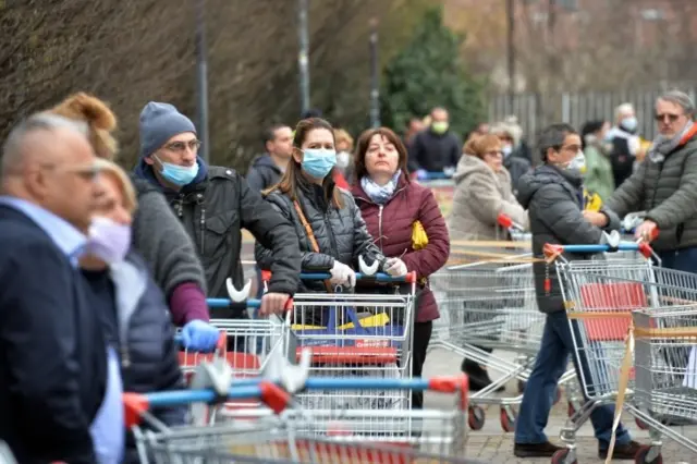 Milano'daki bir süpermarket kuyruğunda bekleyenler