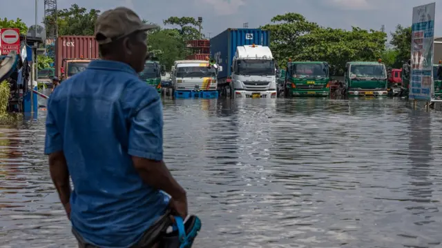 Seorang pekerja pelabuhan melihat kondisi banjir limpasan air laut ke daratan atau rob yang merendam kawasan Pelabuhan Tanjung Emas, Semarang, Jawa Tengah, Selasa (24/05)
