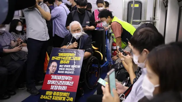 전국장애인차별철폐연대 박경석 대표가 열차 안에서 장애인 권리 예산 보장을 촉구하는 피켓을 목에 걸고 발언하고 있다